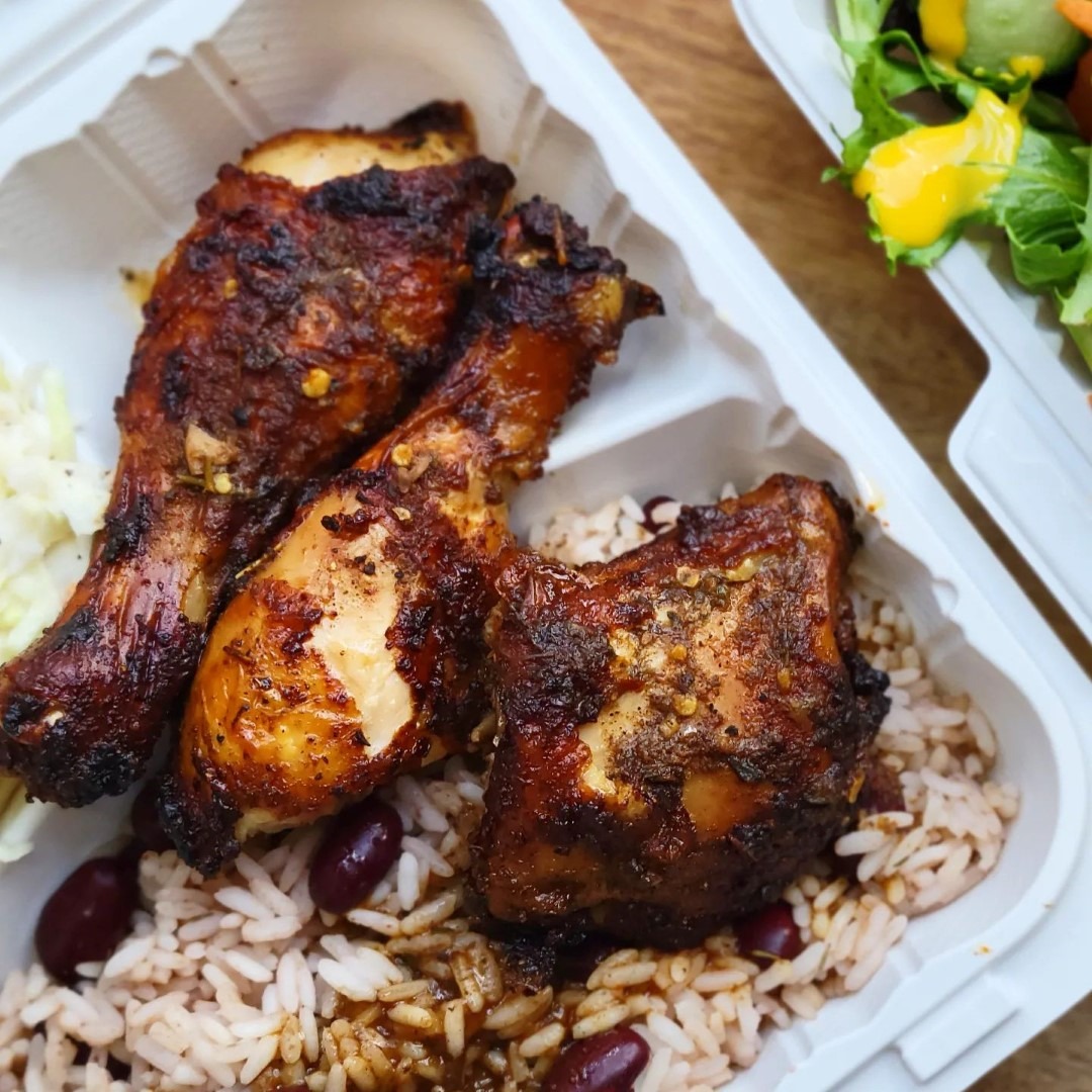 Meal box featuring chopped pieces of jerk chicken on roce and peas